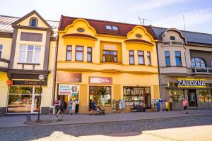 a yellow building with people walking in front of it at Penzión Oliver Humenné in Humenné
