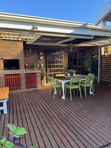 a patio with a table and chairs on a deck at Picasso's Cottage in Gqeberha