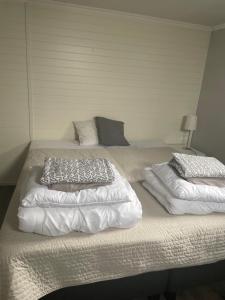 two beds with white blankets and pillows on them at Källarlägenhet Stenungsund in Stenungsund