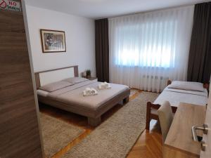 a bedroom with two beds and a table and a window at Apartman Škribulja in Županja