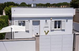 a white house with an umbrella and a fence at Lu Chiapparu B&B in Nardò