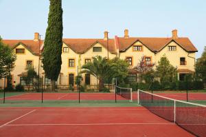 a tennis court in front of a large building at Old England House in Minas de Ríotinto