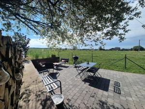 a patio with a table and chairs in a field at Gîte La Petite Villette in Fronville