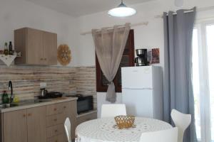 a kitchen with a table and a white refrigerator at Anastazia's Seaside Apartments in Roda