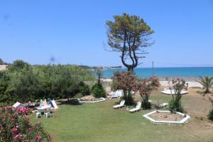 a yard with chairs and a tree and the ocean at Anastazia's Seaside Apartments in Roda +20 photos