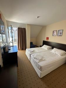 a hotel room with a large bed and a desk at Tropics Hotel by Aleksis in Sveti Vlas