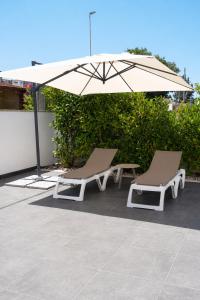 two lounge chairs and an umbrella on a patio at Lu Chiapparu B&B in Nardò