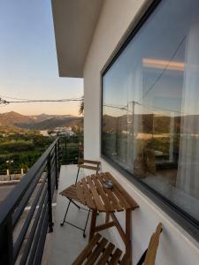 a balcony with a wooden table and a large window at Elina's Era Lounge Apartment in Palekastron