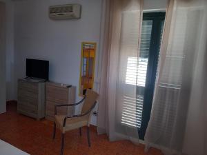 una stanza con una sedia, una televisione e una finestra di TROPEA BIANCA a Tropea