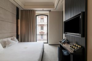 a hotel room with a bed and a flat screen tv at Sparano Palace - Luxury Maison in Bari