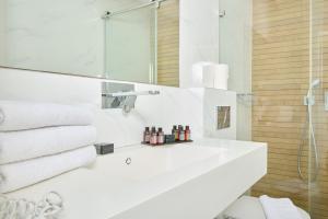 a white bathroom with a sink and a shower at H7 TLV in Tel Aviv +58 photos
