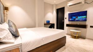 a hotel room with a bed and a flat screen tv at Hotel Jewels at Rajpur Road in Dehradun