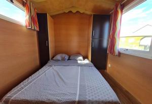 a small bed in a small room with a window at Roulotte tout confort au milieu des animaux in Burthecourt-aux-Chênes
