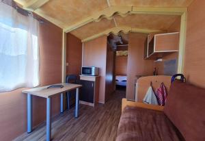a small room with a bed and a table in a tiny house at Roulotte tout confort au milieu des animaux in Burthecourt-aux-Chênes