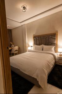 a bedroom with a large white bed with two lamps at AL MIDYAF Appart'Hôtel in El Jadida