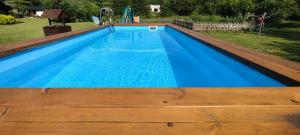 a large swimming pool with blue water and a playground at Chatki Leśniczego z basenem 517-665-624 in Bukowiec