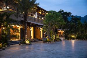 a building with a courtyard with palm trees and lights at Hang Múa Ecolodge Ninh Hoà in Ninh Binh