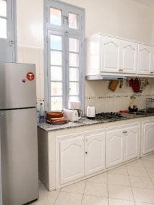a kitchen with white cabinets and a refrigerator at Cosy Art Deco Apart Welcome to James's in Casablanca