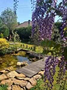 a wooden bridge over a pond in a garden with purple flowers at Le Chalet Lasseube in Lasseube