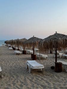 a beach with tables and straw umbrellas on the sand at Tropics Hotel by Aleksis in Sveti Vlas