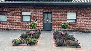 a brick house with a black door and some flowers at Barrierefreie Ferienwohnung Morgentau in Pewsum, 1 - 4 Personen in Krummhörn
