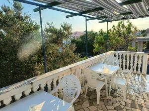 a patio with white chairs and tables on a balcony at Apatmani Čriček in Vlašići