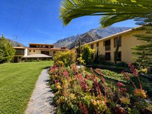 a house with a garden and mountains in the background at Hotel Sol Natura in Ollantaytambo