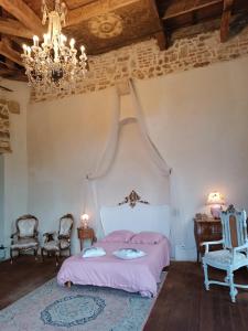 a bedroom with a bed and chairs and a chandelier at Château de la Forie in Saint-Étienne-sur-Usson