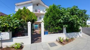 a white house with a gate and trees at Casa Vio parter in Eforie Nord