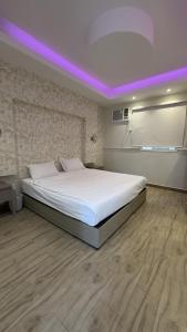 a bedroom with a large white bed with purple lights at منتجع وفلل المرفأ ابها in Abha +38 photos