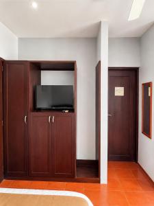 a living room with a tv and wooden cabinets at Hotel Yaltas Inn in Tola