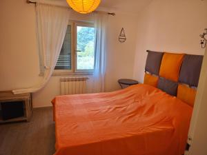 a bedroom with an orange bed and a window at La casetta di Daniela in Sabaudia