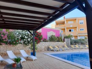 a swimming pool with chairs and a building at Lucie Lime GuestHouse in Luz