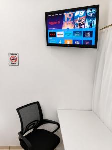 a room with a chair and a tv on a wall at Apartamentos-6-3-8 - Pousada Itapetininga in Itapetininga +20 photos