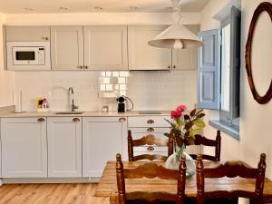 a kitchen with white cabinets and a table and chairs at El Fort d'Ullastret in Ullastret