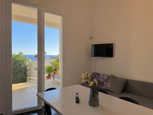 a living room with a couch and a table with flowers at Villa Nauna - Beachfront Villa with Garden & Sea-View Terrace Santa Caterina - Marea Stays Collection in Nardò