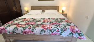 a bed with a floral bedspread on it with two night stands at Apartma REA Izola, pergola & terassa, parking in Izola