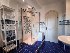 a blue tiled bathroom with a shower and a sink at La casetta di Daniela in Sabaudia +23 photos