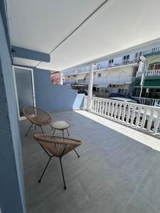 a balcony with a chair and a table and a building at Olympus Apartments in Paralia Katerinis