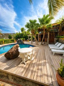 a wooden deck next to a pool with a table and chairs at 3 Bedroom Villa with Pool and Ocean Views in Cap Estate
