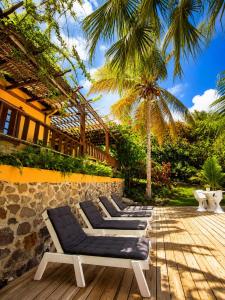 a row of chaise lounge chairs on a wooden deck at 3 Bedroom Villa with Pool and Ocean Views in Cap Estate