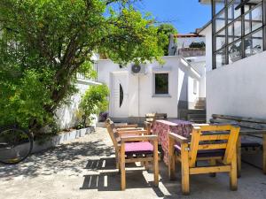 a group of wooden chairs and a table and a tree at El Higo Apartments in Mostar
