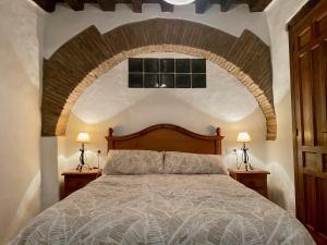 a bedroom with a large bed with a brick wall at Casa Rural El Zaguán in Jimena de la Frontera