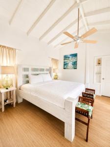 a white bedroom with a large bed and a ceiling fan at 3 Bedroom Villa with Pool and Ocean Views in Cap Estate +16 photos