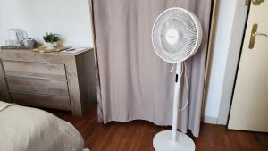 a white fan in a bedroom next to a bed at L'étoile du matin in Terville