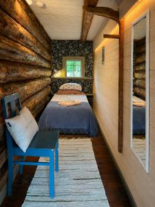 a bedroom in a log cabin with a bed and a chair at Ruhnu Bullers-Gita talu in Ruhnu