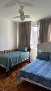 a bedroom with two beds and a ceiling fan at Quarto privativo confortável próximo a ufba, praia, comercio e zoológico in Salvador
