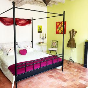 a bedroom with a four poster bed with pink pillows at La savignacoise in Savigny-en-Sancerre