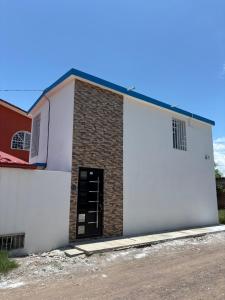 a white building with a door on the side at Tiny House Molino Alto in Ciudad Fernández