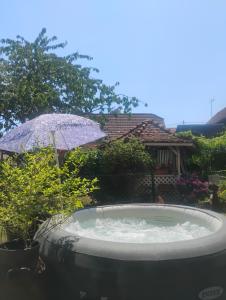 a hot tub with an umbrella in a yard at Villa Le Marronnier, clim, Terrasse, Parking & Spa privé, calme, entre Colmar-Riquewihr et Obernai, Route des vins d'Alsace in Châtenois